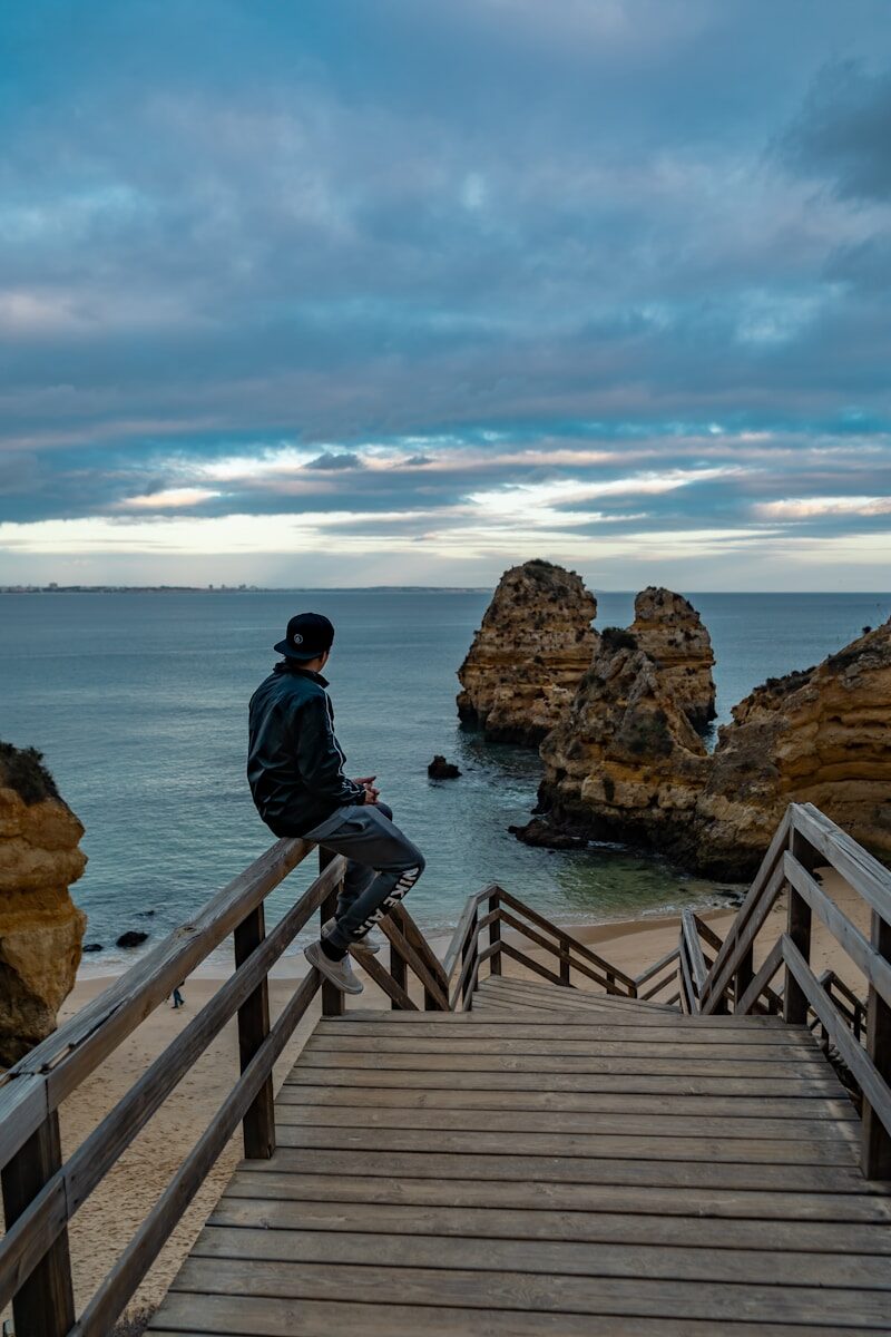 man sitting on brown fence